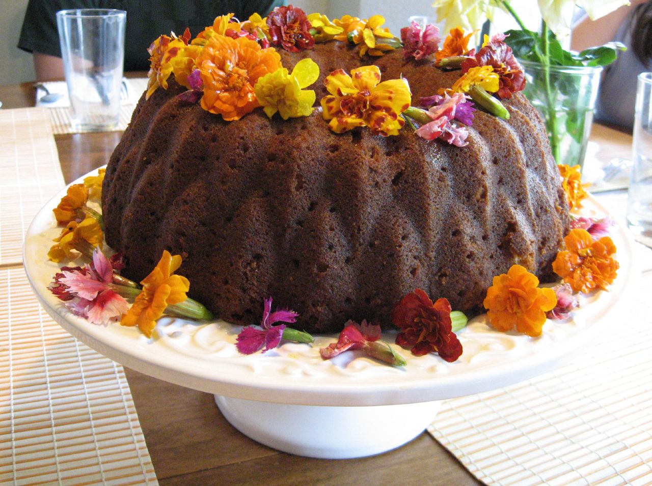 Brown cake on stand decorated with marigolds (edible flowers)